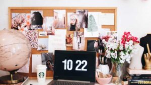 A laptop showing the time stands in front of theis vision board idea including photps and postcards