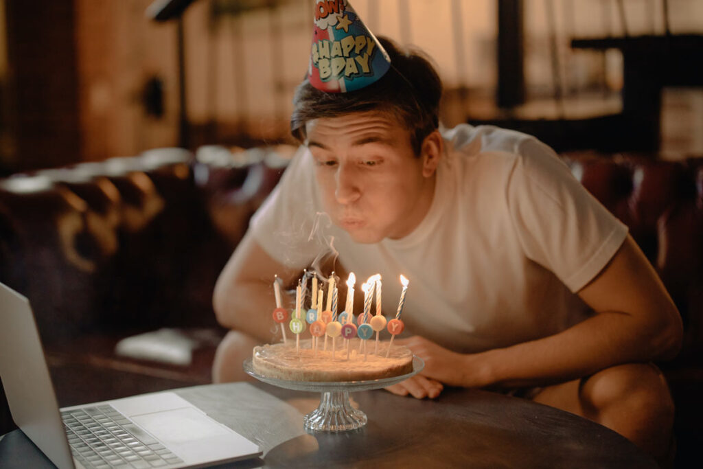 A man celebrates his birthday with a hat and a cake long distance on facetime