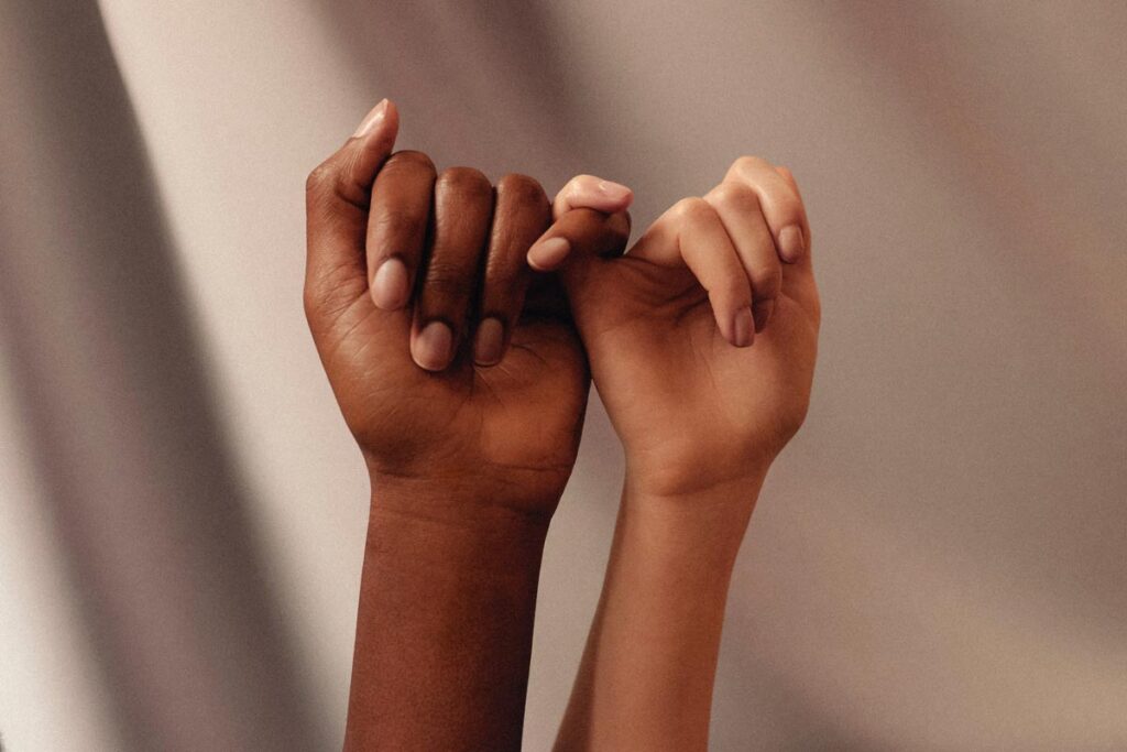 Two women's hands linking little fingers to symbolize ideas to empower women