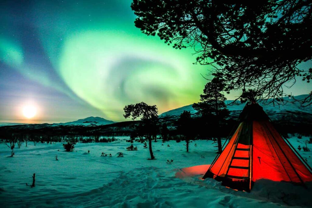 The Northern Lights in the sky over where a tent sits.