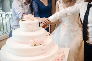 A bridal couple cut the cake together with focus on the cake
