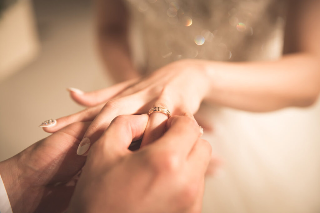 A close up picture of the wedding ring being put on the bride's hand