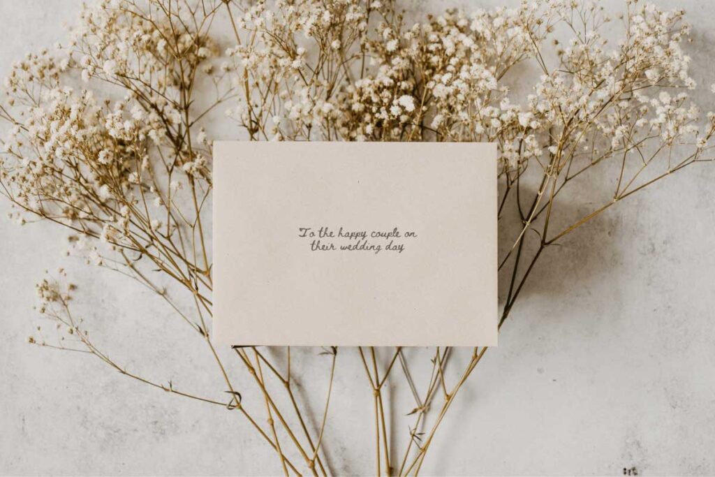 an envelope addressed to the happy couple lying on white flowers