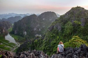 A woman sitting on the rocks of the Mua Cave, a viewpoint known as one of the best in the world