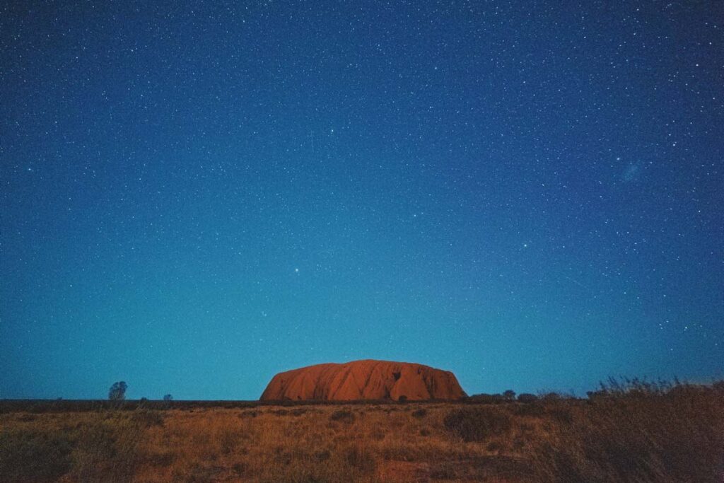 A massive flat rock positioned in front of a view of thousands of stars in the night sky