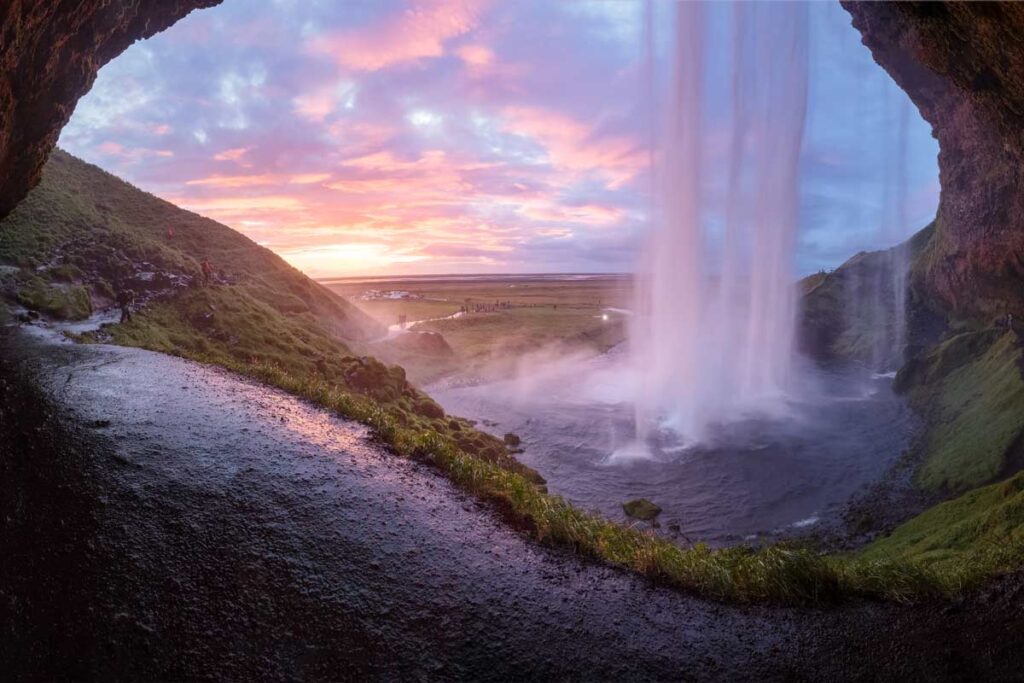 A waterfall seen from within a cave in Iceland, one of the best places for queer people to travel to