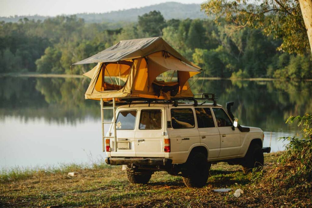 A car parked in front of the lake with a tent on top