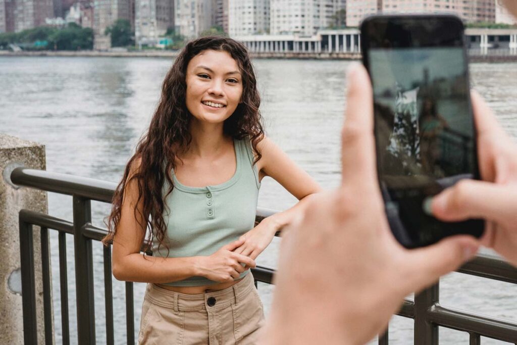 A camera phone taking a picture of a woman in front of a city skyline