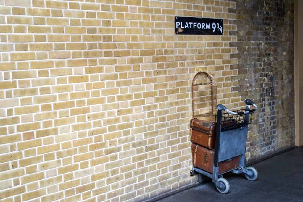 Platform 9 3/4 showing a half burried trolly in the wall from our Harry Potter travel bucket list.