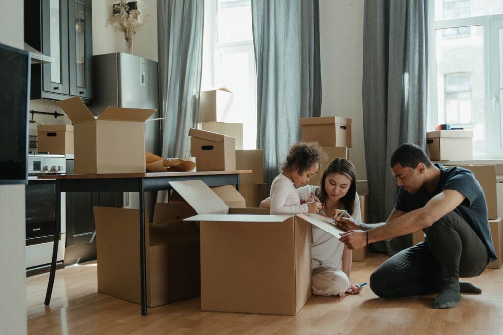 A couple sit with their child amongst moving boxes