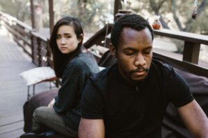 A man and woman sit facing away from each other on a bench