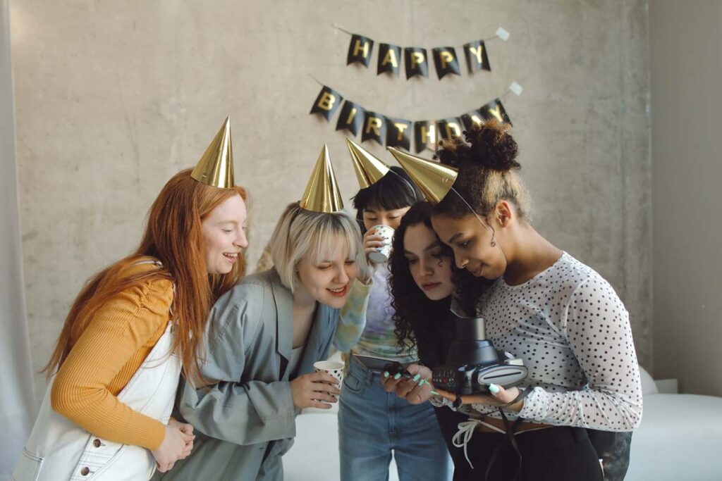 18. Geburtstag feiern im kleinen Kreis zuhause - eine Gruppe sieht sich einen Bild an.