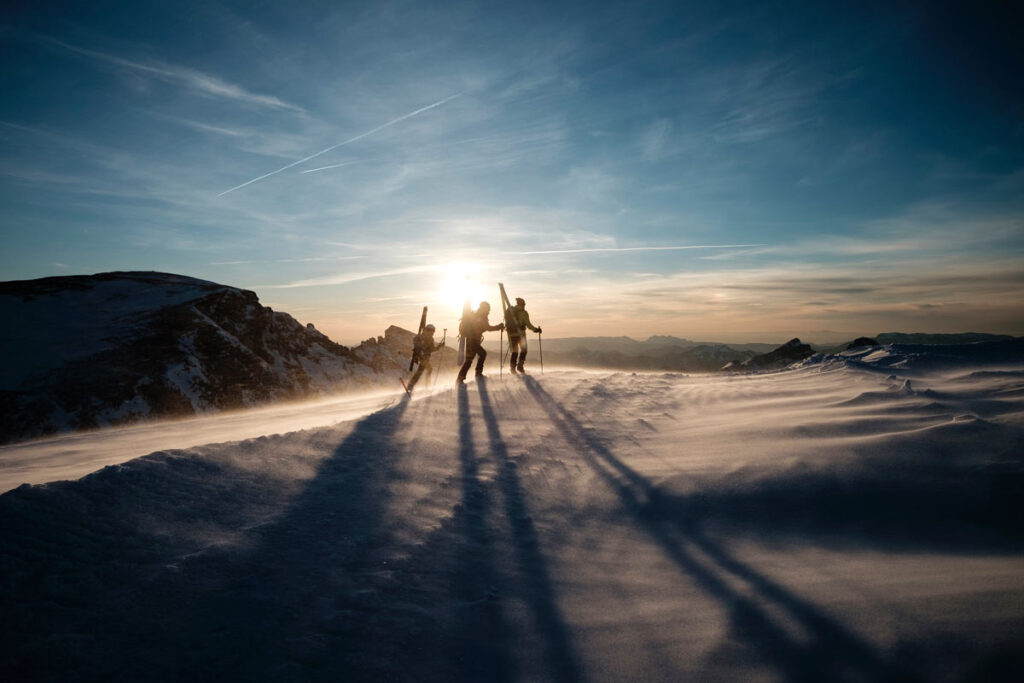 3 Silhouetten im Schnee mit Skis.