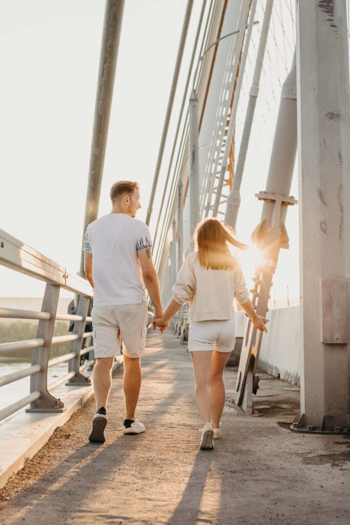 Two people go for a walk at sunset holding hands - one of our free or cheap date ideas