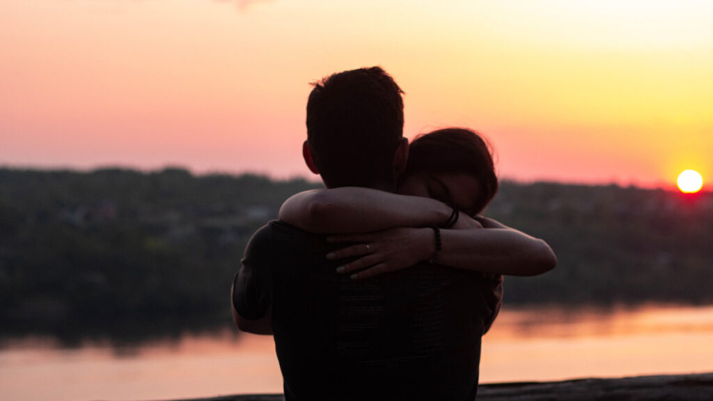 A couple hug in forgiveness as the sun sets