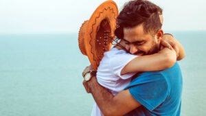 A man and a woman hug emotionally at the beach