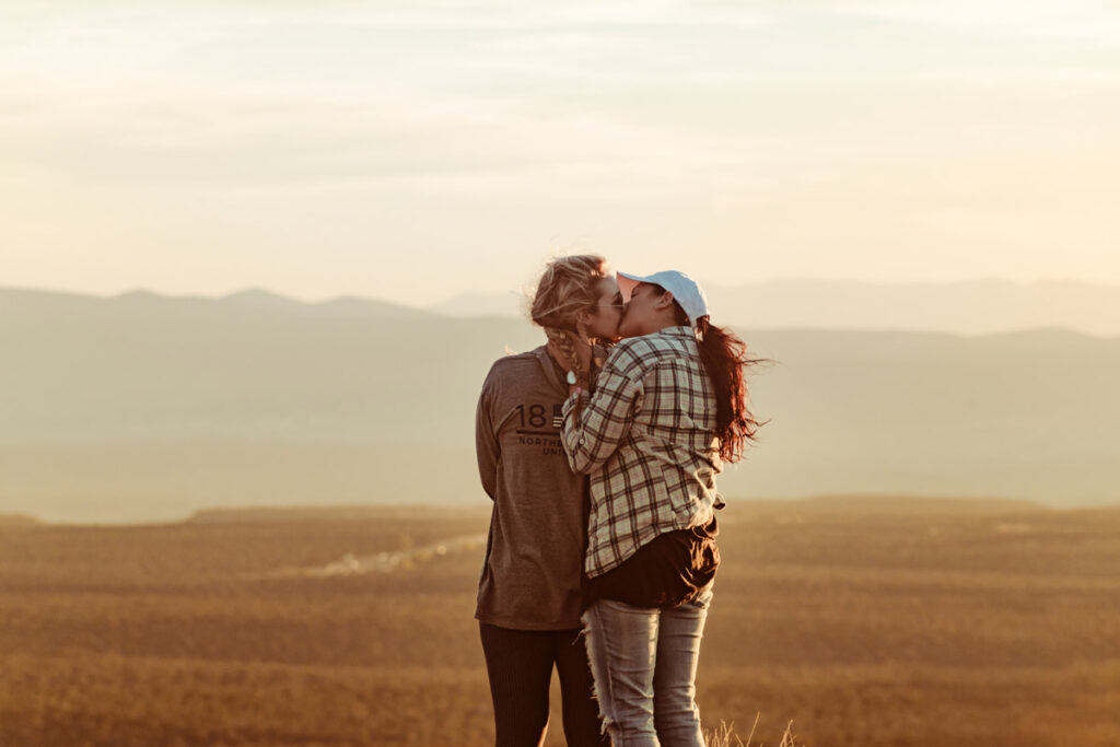 A couple kiss while facing a beautiful landscape at dusk