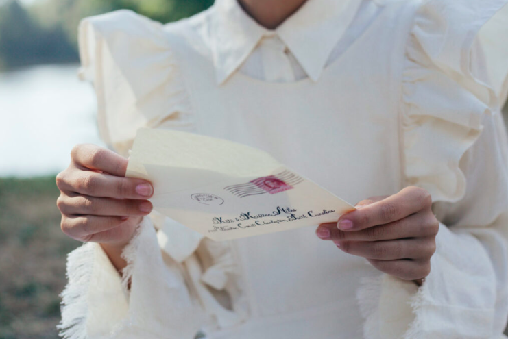 A woman in a white blouse reading a letter